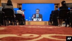 FILE - Chinese Premier Li Keqiang speaks on screen during a press conference by video conferencing at the end of the National People's Congress in Beijing, May 28, 2020. 