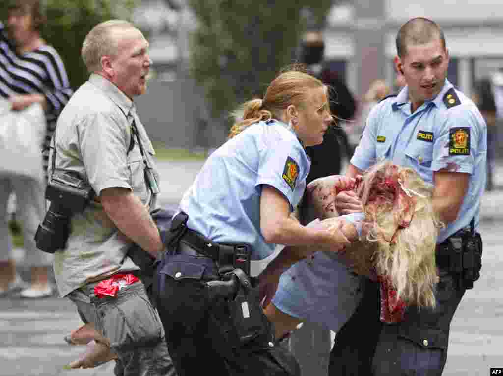 A young victim is helped in the center of Oslo, Friday July 22, 2011, following an explosion that tore open several buildings including the prime minister's office, shattering windows and covering the street with documents. (AP Photo/Scanpix, Winje �jijor