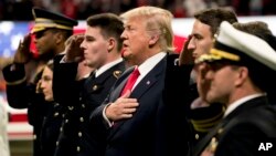 El presidente Donald Trump canta el himno nacional de EE.UU. antes de la final del fútbol universitario en Atlanta, el lunes por la noche.