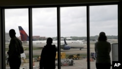 Delta Air Lines passengers watch as a Delta plane taxis at Atlanta's Hartsfield International Airport in Atlanta. Delta Air Lines grounded flights scheduled to leave Monday, Aug. 8, 2016, after experiencing unspecified systems issues. 