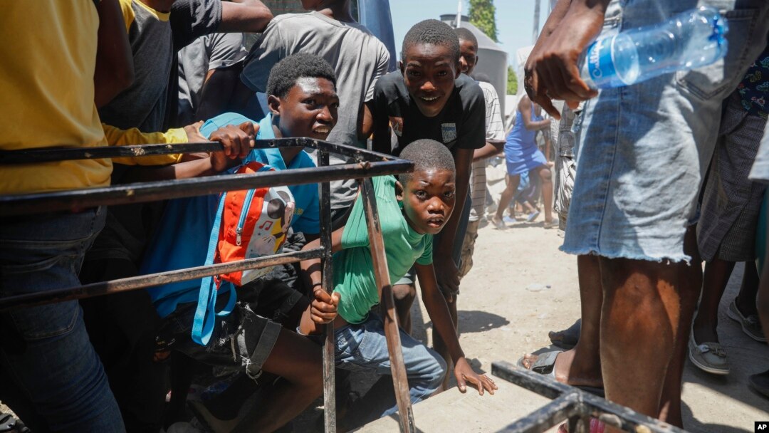 ARCHIVO - Un grupo de menores busca resguardo tras escuchar disparos en una escuela pública que sirve como refugio para la población que ha sido desplazada por la violencia de pandillas, en Puerto Príncipe, Haití, el 22 de marzo de 2024.