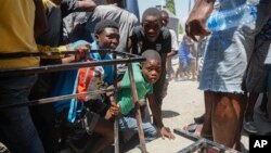 ARCHIVO - Un grupo de menores busca resguardo tras escuchar disparos en una escuela pública que sirve como refugio para la población que ha sido desplazada por la violencia de pandillas, en Puerto Príncipe, Haití, el 22 de marzo de 2024.