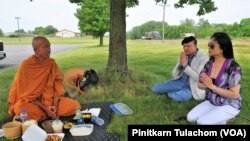 Buddhist monk Sutham Nateetong prays to bless the food given as alms from Mich Siripanya(2nd form R) and Kaysorn Soungpanya (R) at the rest area along the U.S. Route 30 in Columbia City, IN.June 8, 2019. Phra Sutham is during his walk across America to pr