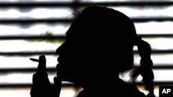 A woman smokes a cigarette in a parking lot in Bangkok, Thailand, May 27, 2010.