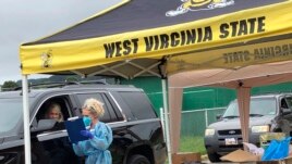 Parents and students arrive in their vehicles for health screenings and temperature checks before moving belongings into residence halls at West Virginia State University campus Friday, July 31, 2020, in Institute, W. Va. (AP Photo/John Raby)