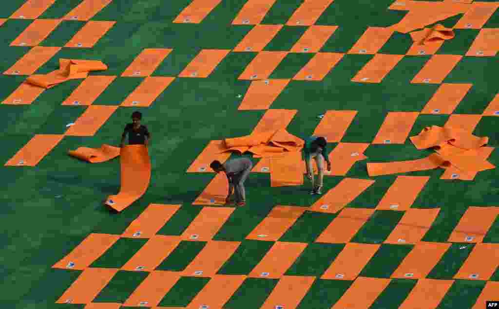 Indian labourers rearrange yoga mats at Forest Research Institute (FRI) ground after a sudden shower on the eve of International Yoga Day in Dehradun.