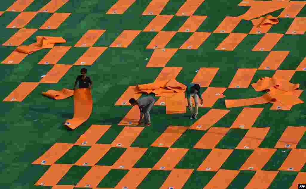 Indian labourers move yoga mats at Forest Research Institute (FRI) ground after a sudden shower the day before International Yoga Day in Dehradun.