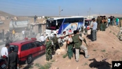 Photo released by the Syrian official news agency SANA shows Syrian troops, journalists, and civilians watching as buses evacuate people from the two pro-government villages of Foua and Kfarya, at Tel el-Eis, the crossing between Aleppo and Idlib provinces, Syria, July 19, 2018.