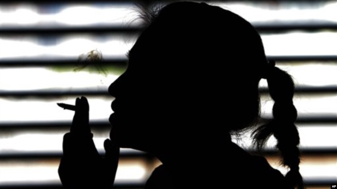 FILE - A woman smokes a cigarette in a parking lot in Bangkok, Thailand, May 27, 2010.