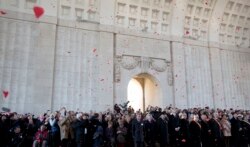 FILE - Red paper poppies fall from the ceiling during an Armistice Day ceremony at the Menin Gate in Ypres, Belgium on Nov. 11, 2014.