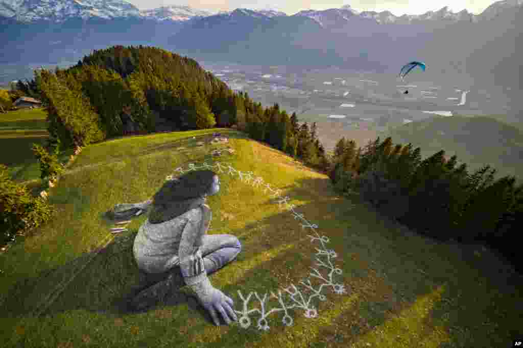 Lukisan di tanah (landart) raksasa yang berjudul "Melampaui Krisis" oleh seniman Saype di resor pegunungan Leysin, Swiss. Karya seni seluas 3.000 meter persegi ini diproduksi dengan cat biodegradable yang terbuat dari bahan-bahan alami, seperti kapur dan batubara dan mengirimkan pesan agar optimis di tengah pandemi Covid-19.