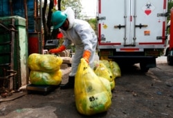 Petugas perusahaan insinerator mengenakan alat pelindung diri tengah mengumpulkan kantong berisi sampah medis (dok: REUTERS/Ajeng Dinar Ulfiana)
