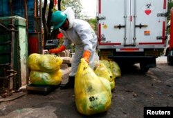 Petugas perusahaan insinerator mengenakan alat pelindung diri tengah mengumpulkan kantong berisi sampah medis (dok: REUTERS/Ajeng Dinar Ulfiana)