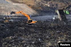 FILE - Workers operate machines at a coal mine at Palaran district in Samarinda, Indonesia, Sept. 14, 2013.