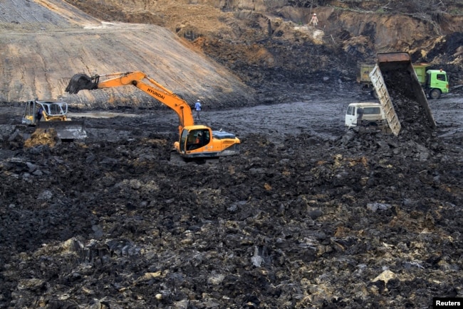 FILE - Workers operate machines at a coal mine at Palaran district in Samarinda, Indonesia, Sept. 14, 2013.