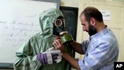 Foto Archivo - 18 de septiembre de 2013 muestra un voluntario ajustando a la máscara de gas de los estudiantes y traje de protección durante una sesión sobre reaccionar a un ataque de armas químicas, en Alepo, Siria.