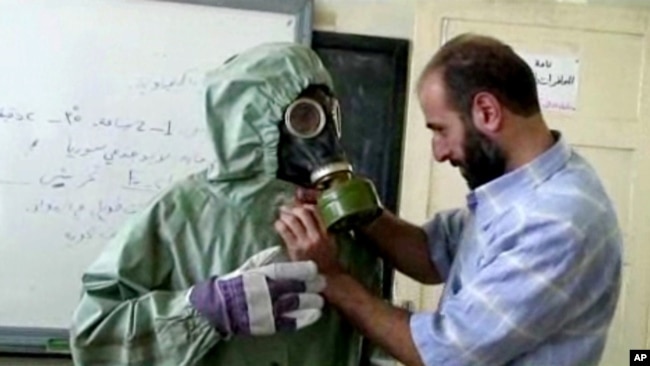 Foto Archivo - 18 de septiembre de 2013 muestra un voluntario ajustando a la máscara de gas de los estudiantes y traje de protección durante una sesión sobre reaccionar a un ataque de armas químicas, en Alepo, Siria.