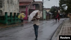 People walk on the street as Tropical Storm Helene passes by near the Cuban coast, Pinar del Rio, Cuba, Sept. 25, 2024.