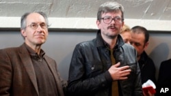 FILE - The new chief editor of French satirical magazine Charlie Hebdo, Gerard Biard, left, and Cartoonist Renald Luzier, known as Luz leave after a press conference in Paris, France.