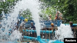 Rescue workers work next to water pumped out of Tham Luang cave complex, where members of an under-16 soccer team and their coach have been found alive, in the northern province of Chiang Rai, Thailand, July 5, 2018.