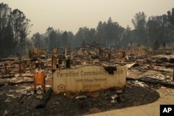 FILE- In this Tuesday, Nov. 13, 2018 file photo a sign stands at a community destroyed by the Camp fire in Paradise, Calif.