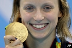 United States' Katie Ledecky shows off her gold medal in the women's 800-meter freestyle medals ceremony during the swimming competitions at the 2016 Summer Olympics, Friday, Aug. 12, 2016, in Rio de Janeiro, Brazil.