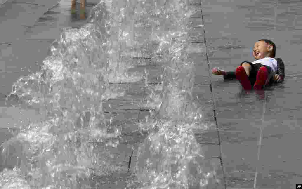 A boy cools off next to an outdoor water fountain in Seoul, South Korea, June 4, 2019.