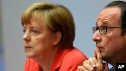 French President Francois Hollande, right, and German Chancellor Angela Merkel attend the Petersberg Climate Dialogue conference in Berlin, Germany, May 19, 2015. 