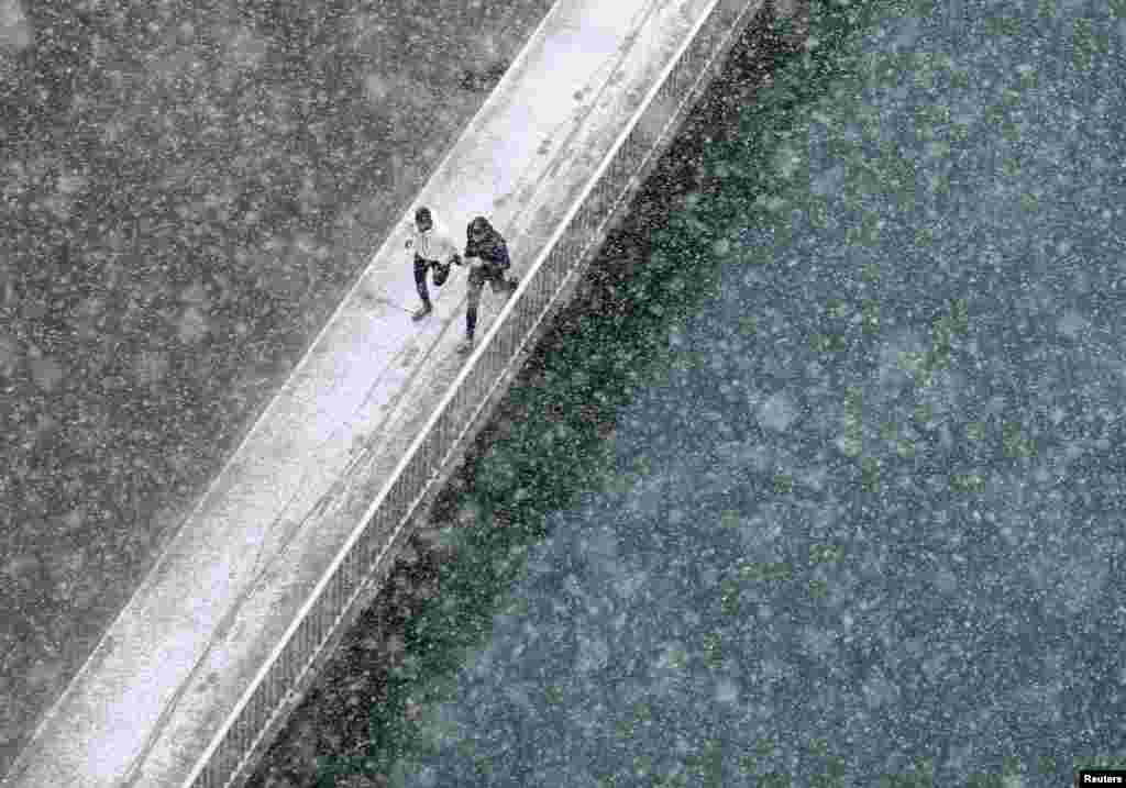 Two joggers run along the embankment of Aare river during the first snowfall in Bern November 21, 2013. Swiss weather service said they expect from 5 to 15 cm of snow on Thursday. 