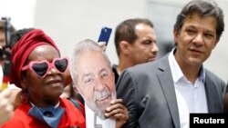 A supporters of former Brazil's President Luiz Inacio Lula da Siva holds a mask next to Fernando Haddad next to the Federal Justice headquarters in Curitiba, Brazil, Nov. 14, 2018. 