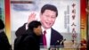 FILE - People walk past a propaganda billboard showing Chinese President Xi Jinping on a street in Beijing, China, March 2, 2018.