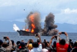 Warga memotret kapal yang terbakar saat pemerintah memusnahkan kapal asing yang ditangkap secara ilegal di perairan Indonesia, di Desa Morela, Pulau Ambon, 1 April 2017. (Foto: Antara via Reuters)