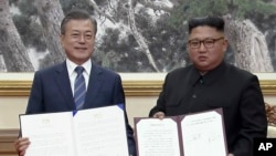 In this image made from video provided by Korea Broadcasting System (KBS), S. Korean President Moon Jae-in, left, and N. Korean leader Kim Jong Un pose after signing documents in Pyongyang, North Korea Wednesday, Sept. 19, 2018.