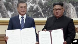 In this image made from video provided by Korea Broadcasting System (KBS), South Korean President Moon Jae-in, left, and North Korean leader Kim Jong Un pose after signing documents in Pyongyang, North Korea, Sept. 19, 2018.