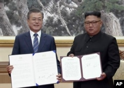 FILE - In this image made from video provided by Korea Broadcasting System (KBS), S. Korean President Moon Jae-in, left, and N. Korean leader Kim Jong Un pose after signing documents in Pyongyang, North Korea, Sept. 19, 2018.