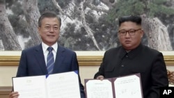 In this image made from video provided by Korea Broadcasting System (KBS), S. Korean President Moon Jae-in, left, and N. Korean leader Kim Jong Un pose after signing documents in Pyongyang, North Korea Wednesday, Sept. 19, 2018.