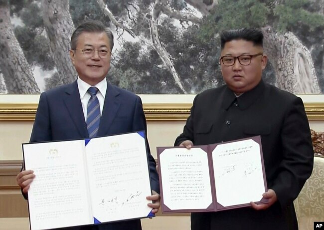 In this image made from video provided by Korea Broadcasting System (KBS), S. Korean President Moon Jae-in, left, and N. Korean leader Kim Jong Un pose after signing documents in Pyongyang, North Korea Wednesday, Sept. 19, 2018.