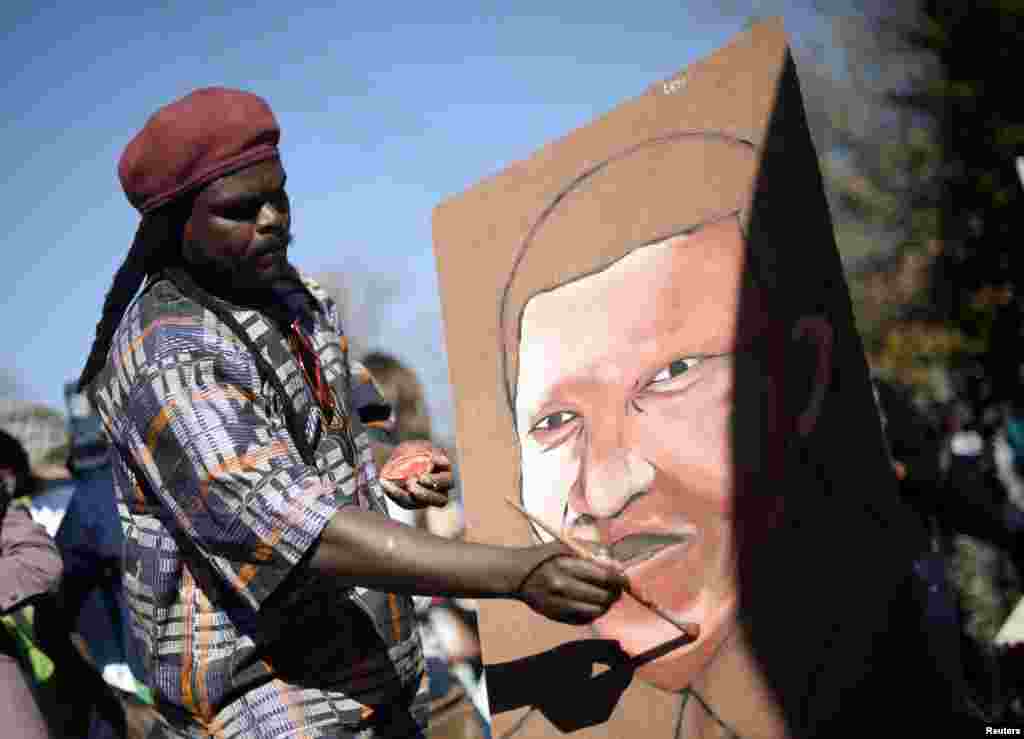 A man paints a portrait of ailing former South African President Nelson Mandela outside the Mediclinic Heart Hospital where he is being treated in Pretoria, June 26, 2013. 