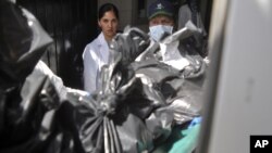 Forensic technicians handle bags containing the remains of people at the morgue after they had been found in two abandoned cars in Guadalajara, May 9, 2012. 