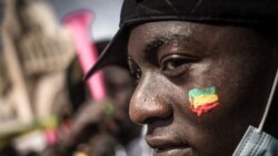 A demonstrator watches the crowd with a Malian flag painted on his cheek, during a mass demonstration in Bamako, on Jan. 14, 2022, to protest against sanctions imposed on Mali and the Junta by ECOWAS.