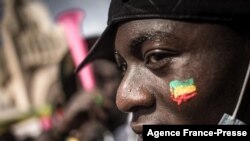 A demonstrator watches the crowd with a Malian flag painted on his cheek, during a mass demonstration in Bamako, on Jan. 14, 2022, to protest against sanctions imposed on Mali and the Junta by ECOWAS.