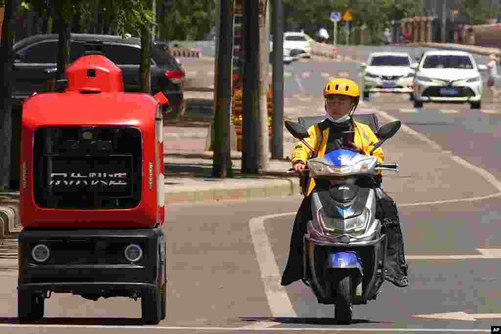 A delivery man passes by an autonomous delivery vehicle from JD.com on the streets of Beijing.