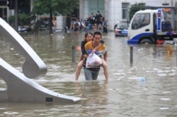 河南省郑州市一名男子背着一名女子趟过满是洪水的街道。 （2021年7月21日）