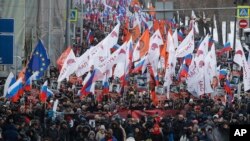 Orang-orang membawa bendera berbagai gerakan, berpawai untuk memperingati tiga tahun pembunuhan pemimpin oposisi Boris Nemtsov di Moskow, Rusia, Minggu, 25 Februari 2018.