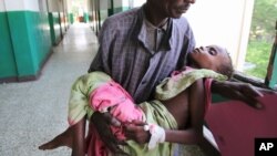 An man carries his malnourished child through the corridors inside Banadir hospital in Somalia's capital, Mogadishu, Aug. 9, 2011. (Reuters)