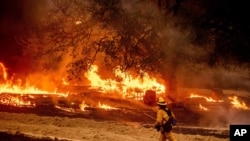 A firefighter passes flames while battling the Glass Fire in a Calistoga, California, vineyard, Oct. 1, 2020.