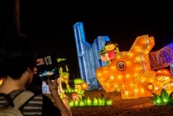 A woman uses her smartphone to take pictures of a lantern display depicting Singapore's iconic architecture and multiracial society during Mid-Autumn Festival celebrations at Jurong Lake Gardens in western Singapore, Sept. 9, 2019.