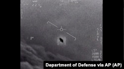 An unexplained object is seen at center high along the clouds, traveling against the wind in this image from video provided by the Department of Defense labelled Gimbal, from 2015. (Department of Defense via AP)