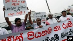 A Sri Lankan human rights activist shouts slogans as others hold a banner and placards against the weekend arrests of right activists in Colombo, Mar. 19, 2014.