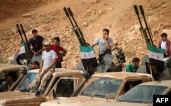 Syrian rebel fighters man anti-aircraft guns mounted in the back of pickup trucks during a military parade near the southern city of Daraa on June 7, 2018.